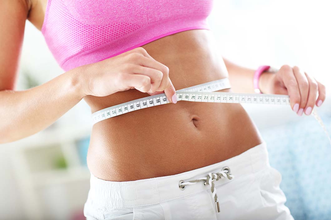 Image of woman holding tape measure showing newly sculpted abs.